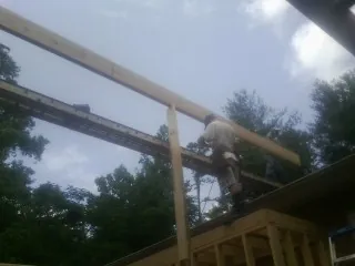 Carpenter setting a ridge beam over a new addition frame — Ice Dam Removal by Roofing Brothers in Dime Box