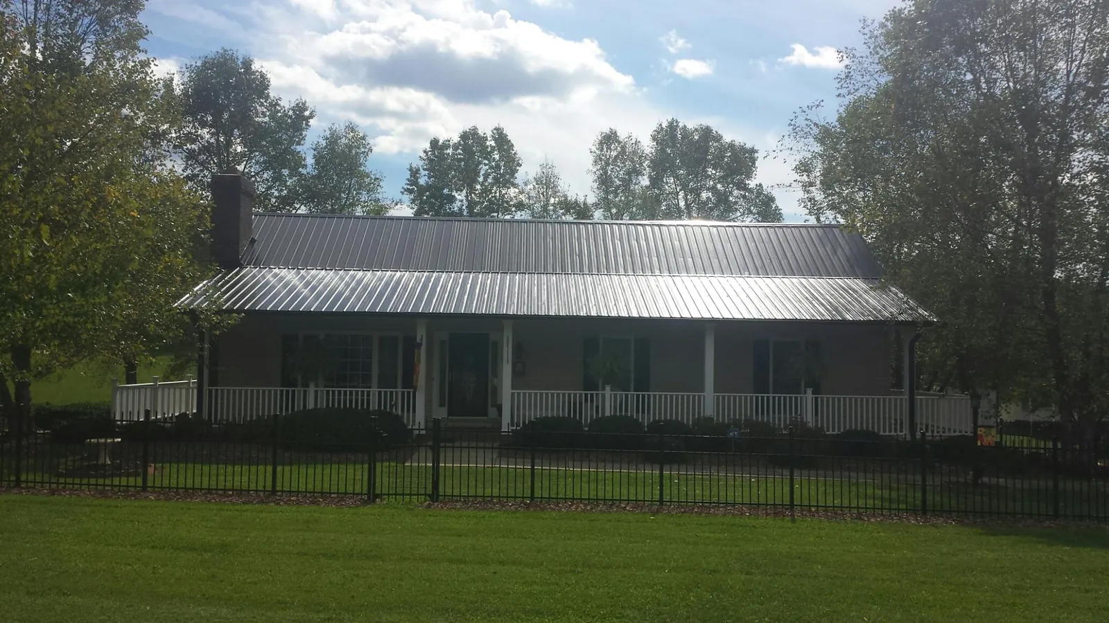 Gray metal roof on a brick ranch with a full width front porch — Gutter Guard Installation work by our crew in Dime Box