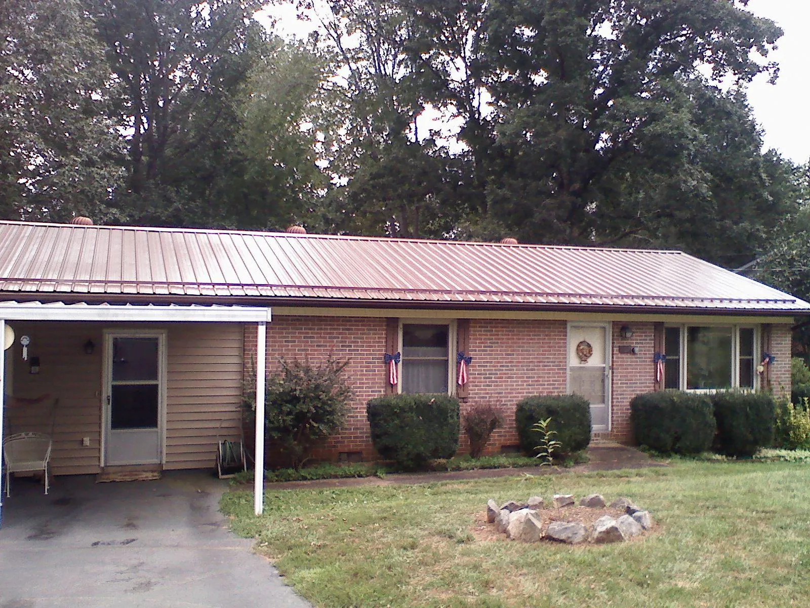 Bronze metal roof and carport on a brick ranch home — Roof Repair work by our crew in Dime Box